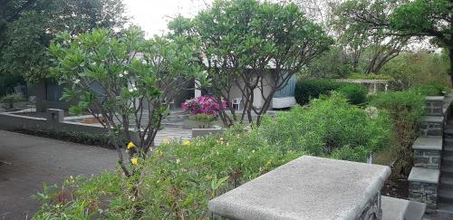 eine Bank in einem Garten mit Bäumen und Blumen in der Unterkunft The Meadows Resort and Spa in Aurangabad