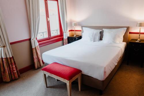 een slaapkamer met een groot wit bed en een rode kruk bij Paleis Hotel in Den Haag