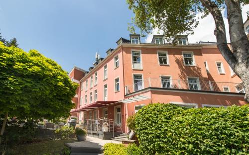 un grande edificio rosa con alberi di fronte di Hotel Oranien Wiesbaden a Wiesbaden