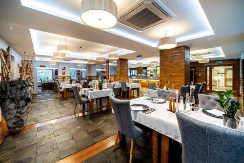 une salle à manger avec des tables et des chaises blanches dans l'établissement Hotel Żywiecki Medical SPA & Sport Żywiec, à Żywiec