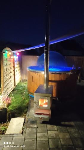 een kachel in een achtertuin 's nachts met een zaklamp bij Uroczy domek z baliá z jacuzzi in Władysławowo