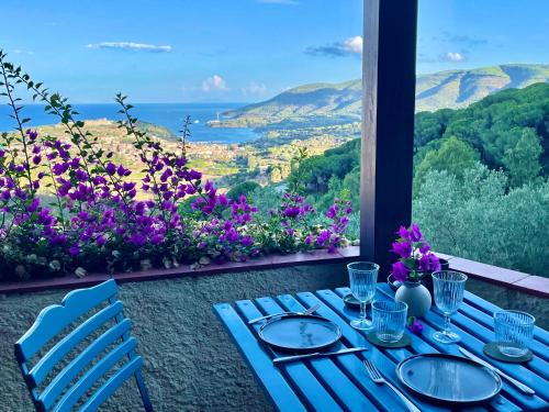 a blue table with a view of the ocean and flowers at Aria di Collina - Isola d'Elba in Porto Azzurro