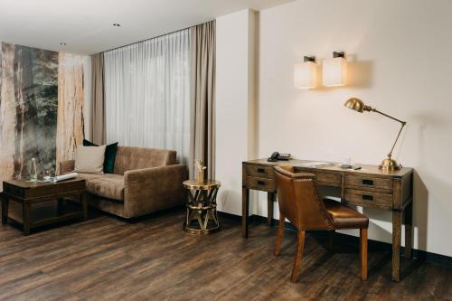 Cette chambre comprend un bureau, une chaise et un canapé. dans l'établissement Hotel Forsthaus Nürnberg Fürth, à Fürth