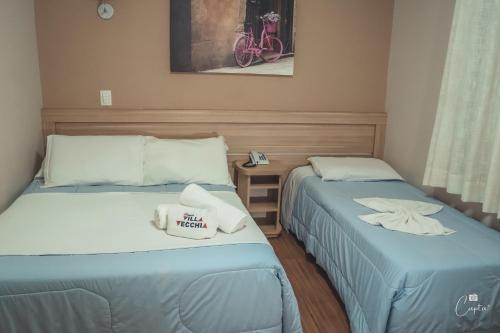 two beds in a hotel room with towels on them at Pousada Villa Vecchia in Canela