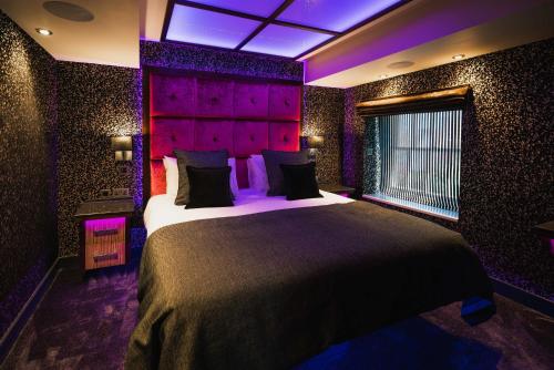 a bedroom with a large bed with purple lighting at Church Suites by The Cranleigh Boutique in Bowness-on-Windermere