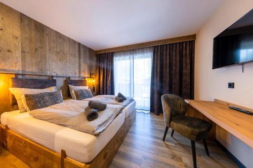 - une chambre avec un lit, un bureau et une télévision dans l'établissement Herz3 Hotel Bar Restaurant Trattoria, à Hollersbach im Pinzgau