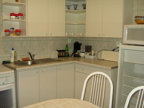 a kitchen with white cabinets and a sink and a microwave at Szigeti B&B in Bogács