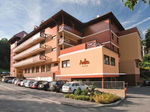 a building with cars parked in a parking lot at Hotel Ambra in Luhačovice