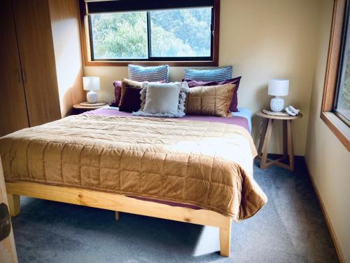 een slaapkamer met een groot bed met kussens en een raam bij Red ceder cottage - Great ocean road - Port Campbell in Port Campbell