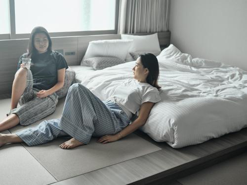 2 femmes assises à l'étage, à côté d'un lit dans l'établissement fav HIROSHIMA STADIUM, à Hiroshima