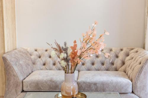 un vase avec des fleurs sur une table devant un canapé dans l'établissement AGORA luxury BOUTIQUE HOTEL, à Loutraki