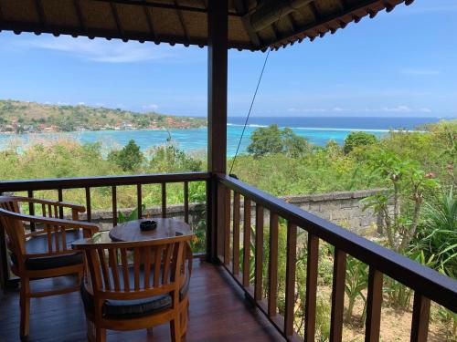 uma varanda com uma mesa e cadeiras e o oceano em Bukit Permata Lembongan em Nusa Lembongan