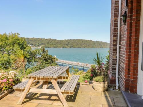 a wooden table and benches on a patio with a view of the water at Bryn Ogwen in Bangor