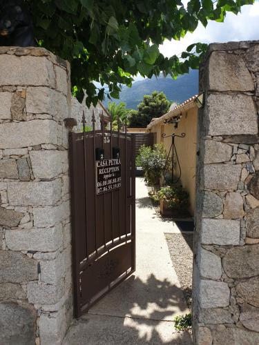 un portail avec un panneau placé à côté d'un mur en pierre dans l'établissement Casa Petra, à Corte