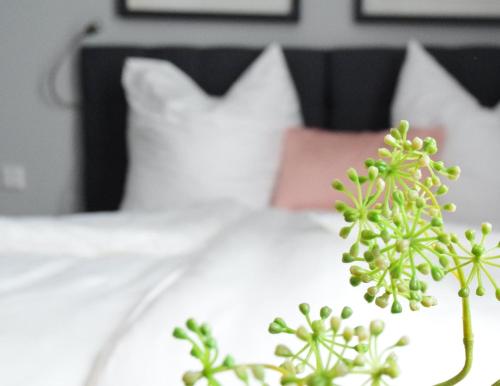 a white bed with white pillows and a green plant at OLÉ Hotel in Hamburg