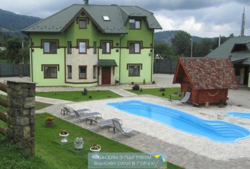 a house with a swimming pool in front of it at Emerald House in Mykulychyn