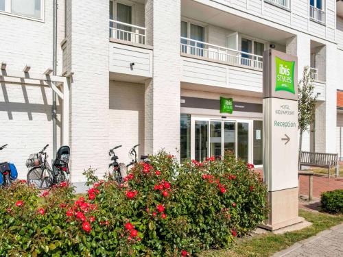 a sign in front of a building with red flowers at ibis Styles Nieuwpoort in Nieuwpoort