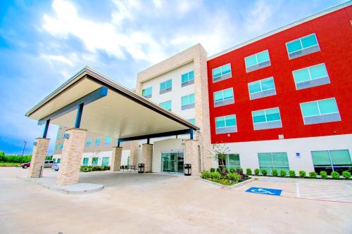 een groot rood-wit gebouw met een parkeerplaats bij Holiday Inn Express & Suites - Houston IAH - Beltway 8, an IHG Hotel in Houston