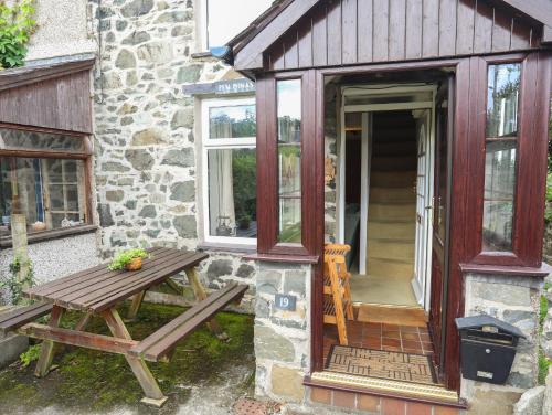 a picnic table in front of a stone building with a door at Pen Dinas in Bangor