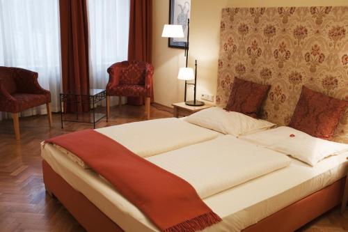 a bedroom with a large bed with two chairs at Hotel Villa Florentina in Frankfurt/Main