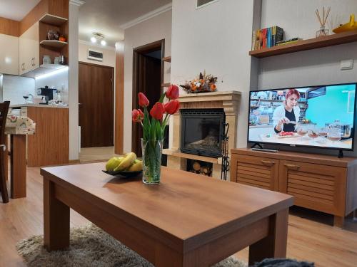 een woonkamer met een vaas met bloemen en een televisie bij Lusi Holiday, Смолянски езера in Smolyan