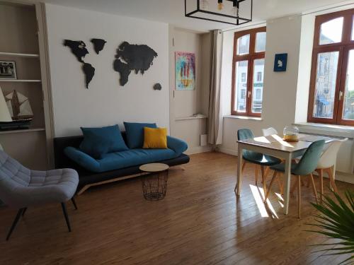 a living room with a blue couch and a table at Le Godefroy de Bouillon in Boulogne-sur-Mer