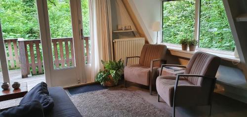 sala de estar con 2 sillas y 2 ventanas en Gezellige bungalow met zwembad op het park, en Durbuy