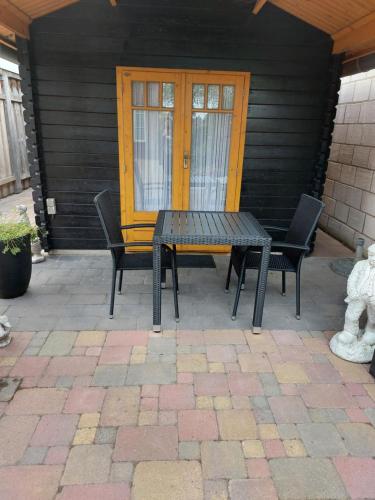 a table and chairs on a patio with a yellow door at De Poldersteeg 