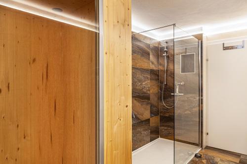 bagno con pareti in legno e doccia in vetro. di Ferienwohnung Galerie Kaiser a Mayrhofen