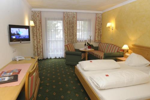 Habitación de hotel con cama y sala de estar. en Hotel Stegmühlhof, en Mauterndorf