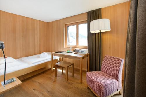 Zimmer mit einem Bett, einem Stuhl und einem Fenster in der Unterkunft Hotel Gasthof Krone in Hittisau