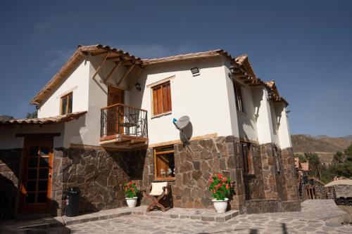 uma casa com flores em frente em Lodge El Portal de Qopuy em Coporaque