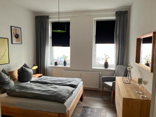 1 dormitorio con 1 cama, escritorio y ventanas en Schmuckstück im Herzen Rostocks mit grüner Oase, en Rostock