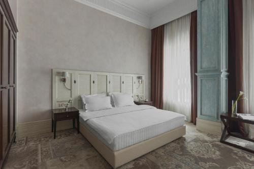 Un dormitorio con una gran cama blanca y una ventana en Ribas Duke Boutique Hotel, en Odessa