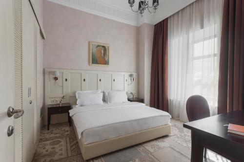 1 dormitorio con cama, escritorio y ventana en Ribas Duke Boutique Hotel, en Odessa