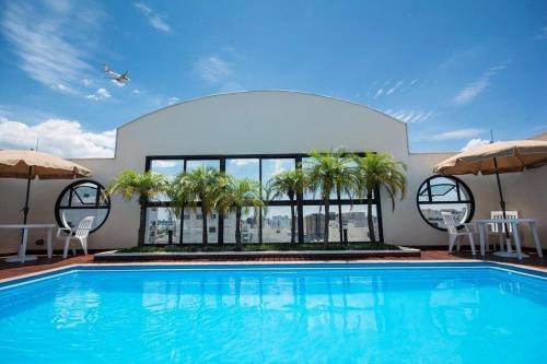 une piscine bordée de palmiers et un bâtiment dans l'établissement The Palace TV Giratória Limpeza Diária UH1303, à São Paulo