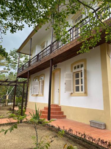 a white house with a porch and a balcony at Roça Vale dos Prazeres in São Tomé