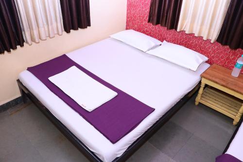 uma cama com um cobertor roxo e branco em Hotel laxminarayan em Shirdi