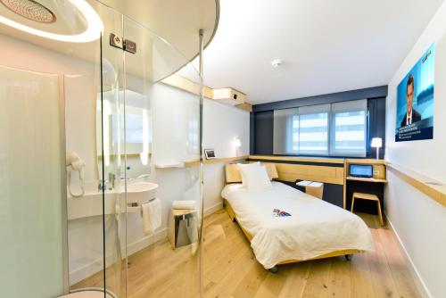 um pequeno quarto com uma cama e um chuveiro em Nomad Paris Roissy CDG em Le Mesnil-Amelot