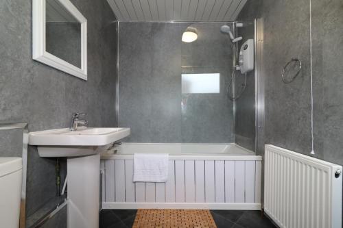 La salle de bains est pourvue d'un lavabo, d'une baignoire et d'une douche. dans l'établissement Signature - Carnoustie House, à East Kilbride