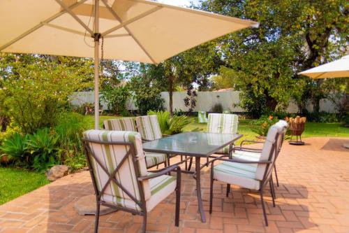 una mesa y sillas con una sombrilla en el patio en Burley House by Ulendo, en Lilongwe