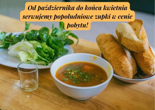 una mesa con un tazón de sopa y un plato de pan en Villa Meduza, en Kołobrzeg