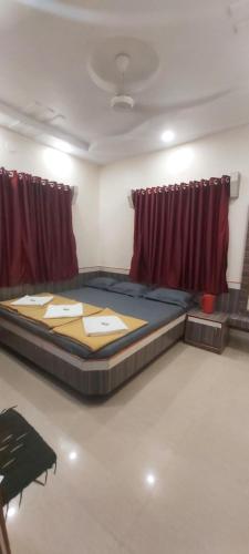 un grande letto in una stanza con tende rosse di Sai Raghunandan Guest House a Shirdi