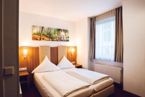 een slaapkamer met een bed met witte lakens en een raam bij Hotel Domblick Garni in Keulen