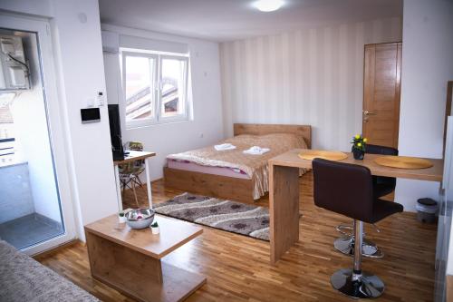 1 dormitorio con cama, escritorio y mesa en Demir Apartmani, en Novi Pazar