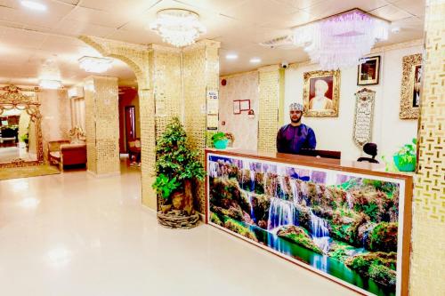 a man is standing at a counter in a lobby at Capital O 141 Golden Rays Hotel in Ibrā