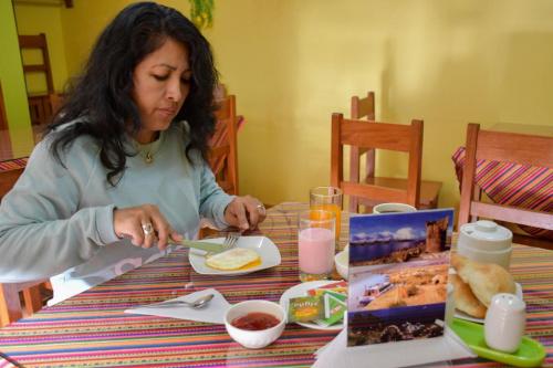 una mujer sentada en una mesa con un plato de comida en Olimpo Inn, en Puno