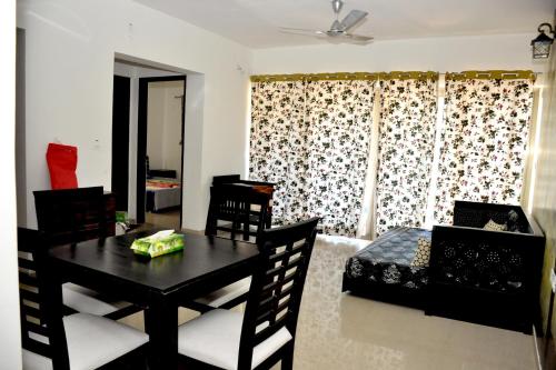 uma sala de estar com uma mesa e cadeiras pretas e um quarto em 2BHK Lake View Apartment em Lavasa