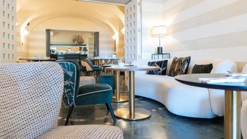 a restaurant with tables and chairs and a couch at Hotel Ancora in Verbania