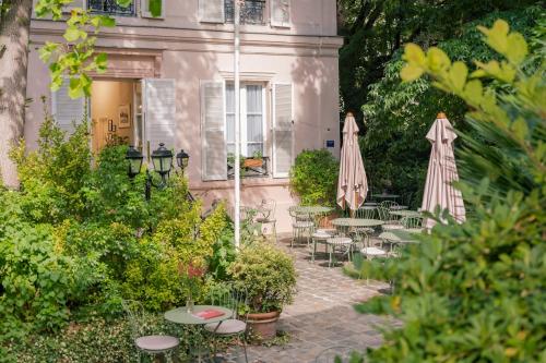 un patio con mesas y sombrillas frente a un edificio en Hotel des Grandes Ecoles, en París